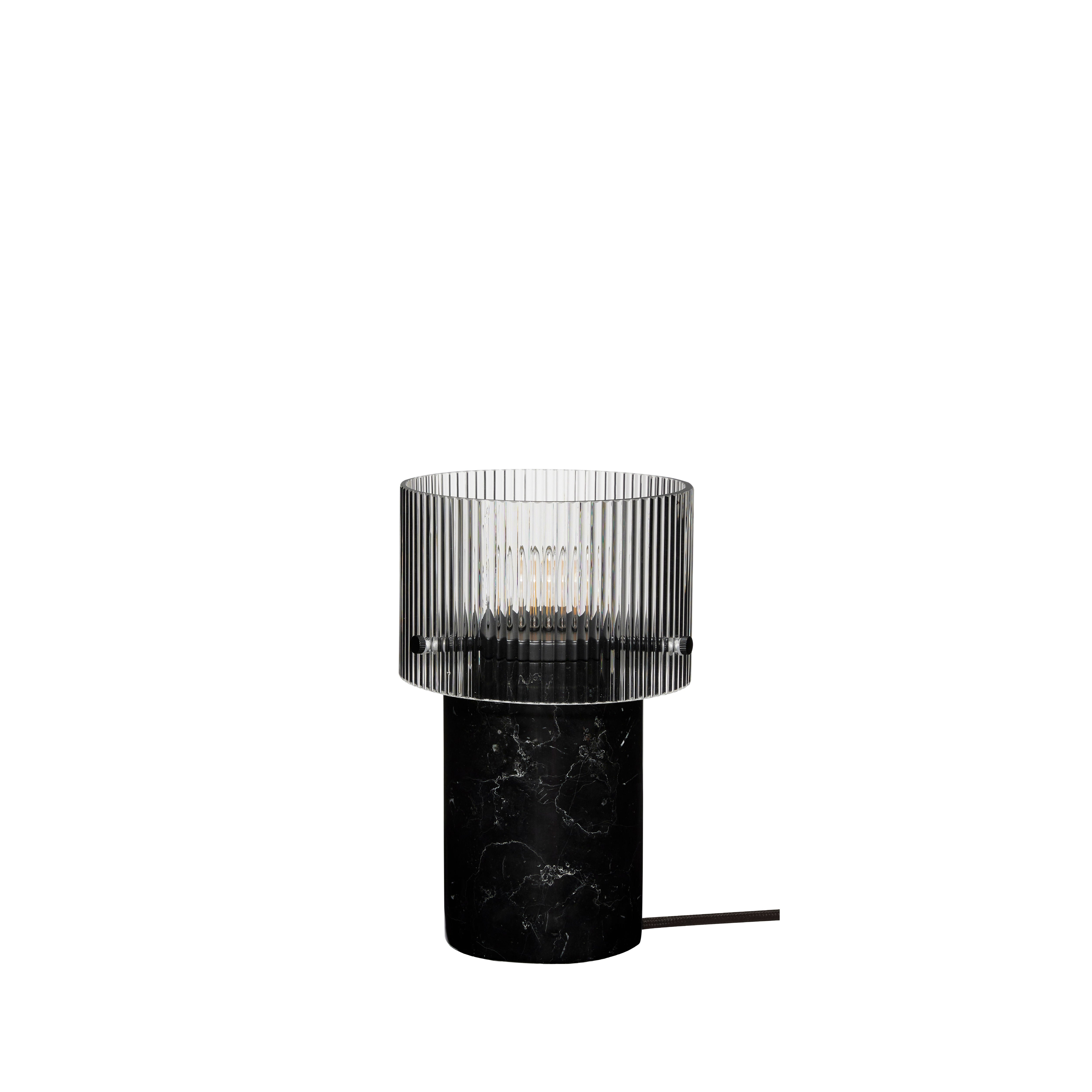 Die Tischleuchte "Revolve" in Schwarz besticht durch ihren geriffelten Glasschirm und den marmorierten Sockel in Schwarz und Weiß, verleiht jedem Raum Eleganz und Stil und eignet sich perfekt für Nachttische, Konsolentische oder Sideboards